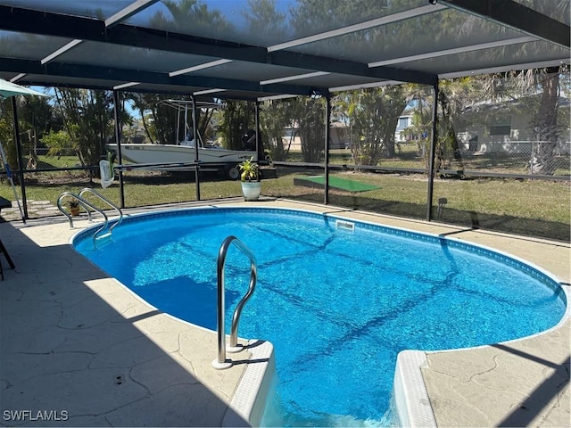 outdoor pool with glass enclosure, a lawn, and a patio