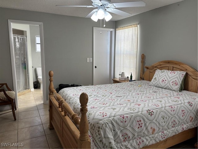 bedroom featuring light tile patterned floors, connected bathroom, ceiling fan, a textured ceiling, and a closet