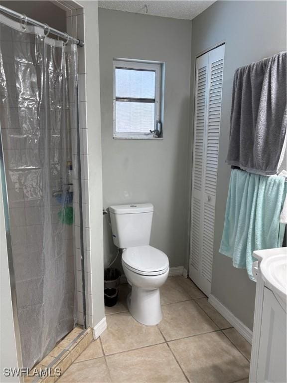 bathroom with tile patterned flooring, vanity, baseboards, a closet, and a stall shower