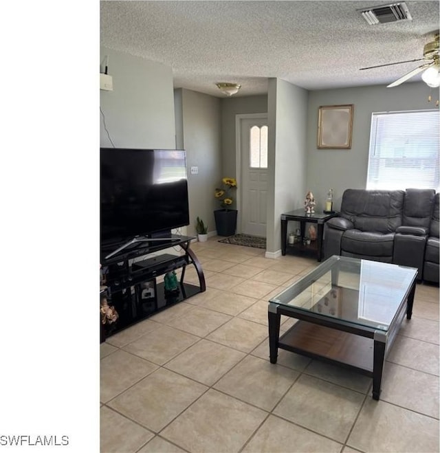 living area with visible vents, ceiling fan, a textured ceiling, and light tile patterned flooring