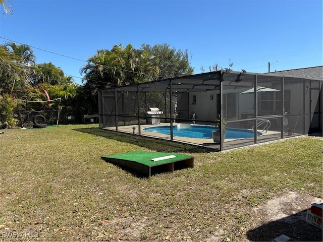 pool featuring glass enclosure and a yard