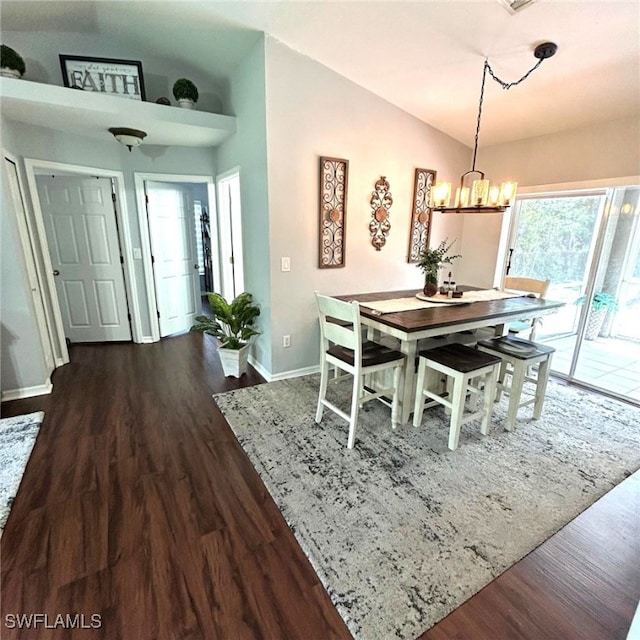 dining room with dark wood-type flooring, a chandelier, vaulted ceiling, and baseboards