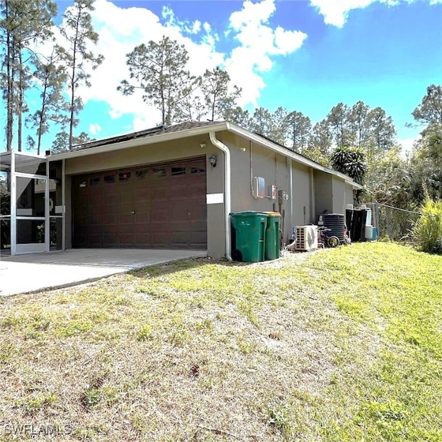 view of home's exterior with an attached garage, driveway, a yard, stucco siding, and ac unit