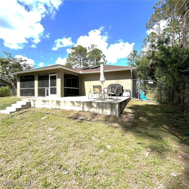 back of property with stucco siding, a lawn, a sunroom, a patio area, and fence