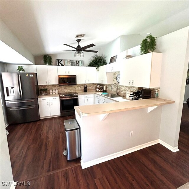 kitchen with stainless steel appliances, light countertops, vaulted ceiling, a sink, and a peninsula