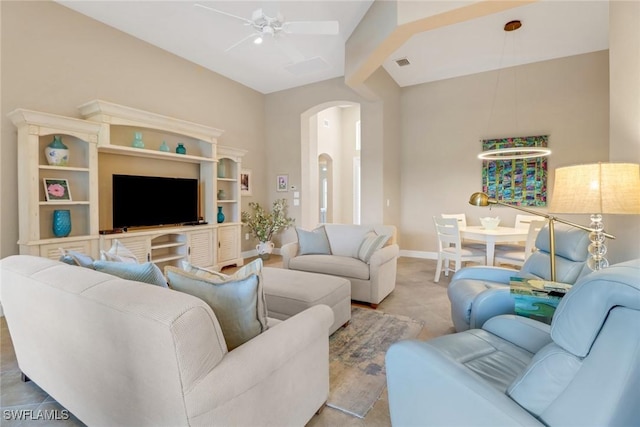 living room with arched walkways, light carpet, visible vents, a ceiling fan, and baseboards