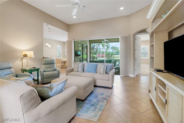 living area with light tile patterned floors, arched walkways, baseboards, ceiling fan, and recessed lighting