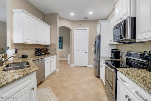 kitchen with arched walkways, visible vents, stainless steel appliances, white cabinetry, and a sink