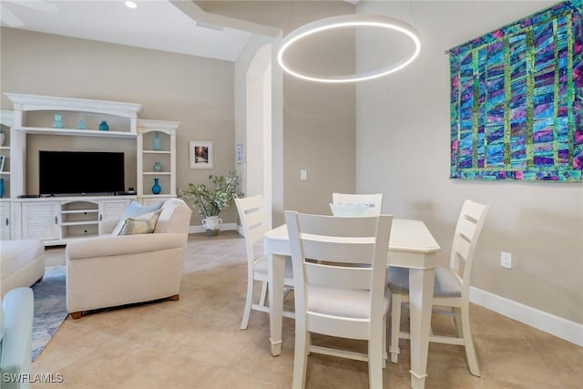 dining space with light tile patterned floors, baseboards, and arched walkways