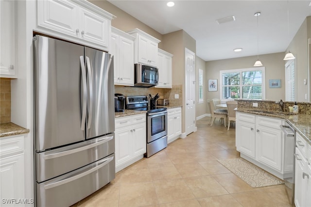 kitchen with stainless steel appliances, decorative backsplash, white cabinets, a sink, and light tile patterned flooring