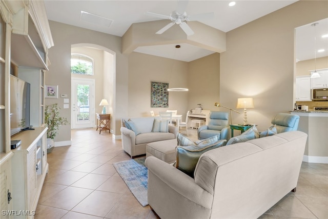 living area with baseboards, arched walkways, a ceiling fan, and light tile patterned flooring