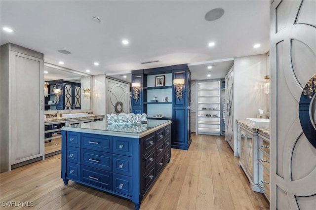 kitchen with light countertops, light wood finished floors, a center island, and blue cabinets