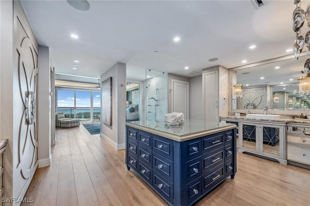 kitchen featuring light wood-type flooring, blue cabinetry, light countertops, and a sink