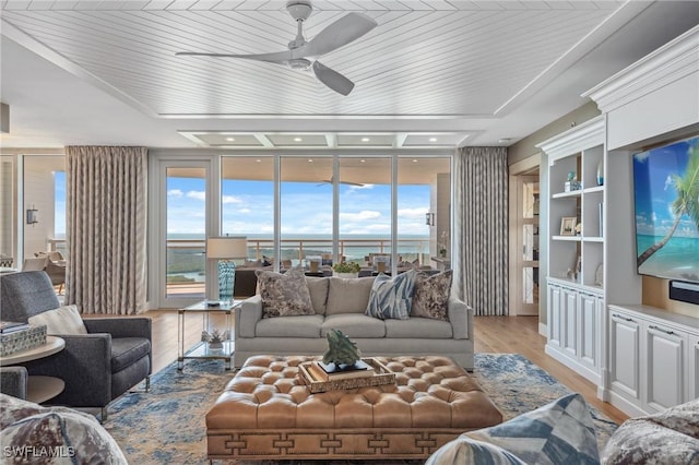 living area featuring light wood-type flooring, a healthy amount of sunlight, a wall of windows, and a ceiling fan