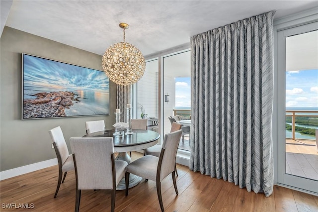 dining space featuring expansive windows, baseboards, wood finished floors, and an inviting chandelier