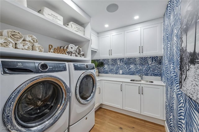 clothes washing area with cabinet space, light wood-style floors, separate washer and dryer, a sink, and recessed lighting