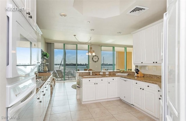 kitchen featuring white appliances, visible vents, a peninsula, white cabinetry, and a sink