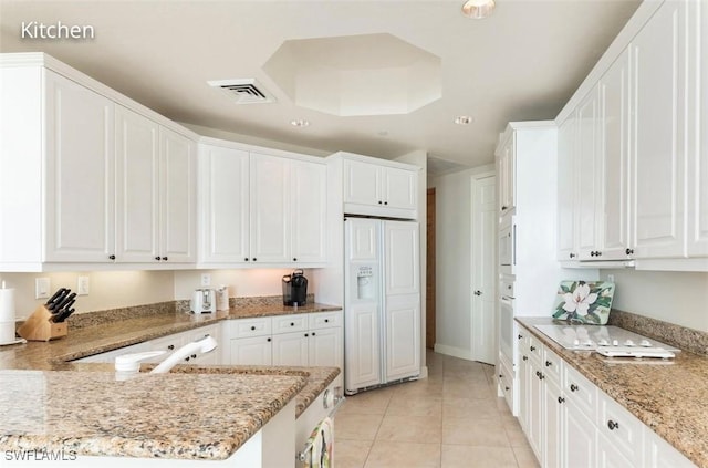 kitchen with white appliances, light tile patterned floors, and white cabinetry