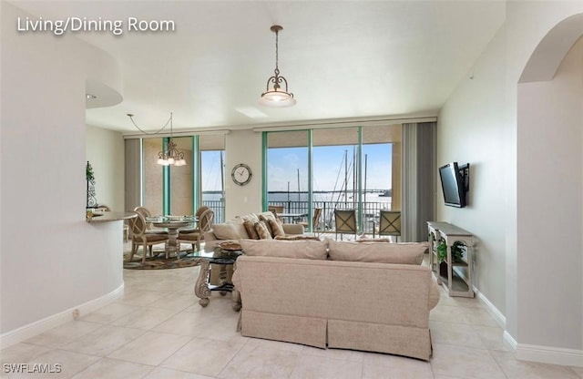 tiled living room with baseboards, arched walkways, and a notable chandelier