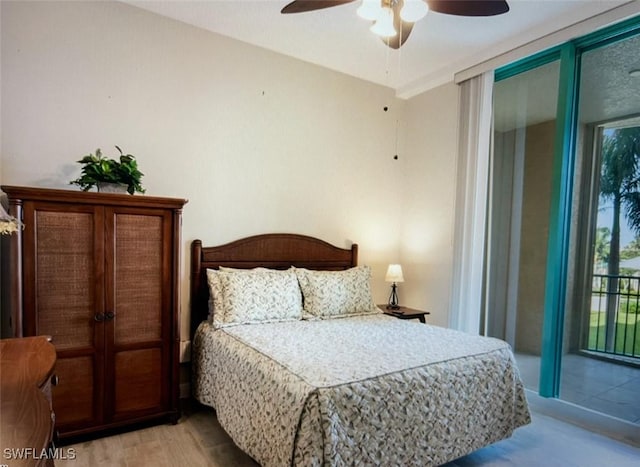 bedroom with access to outside, a wall of windows, light wood-style flooring, and a ceiling fan