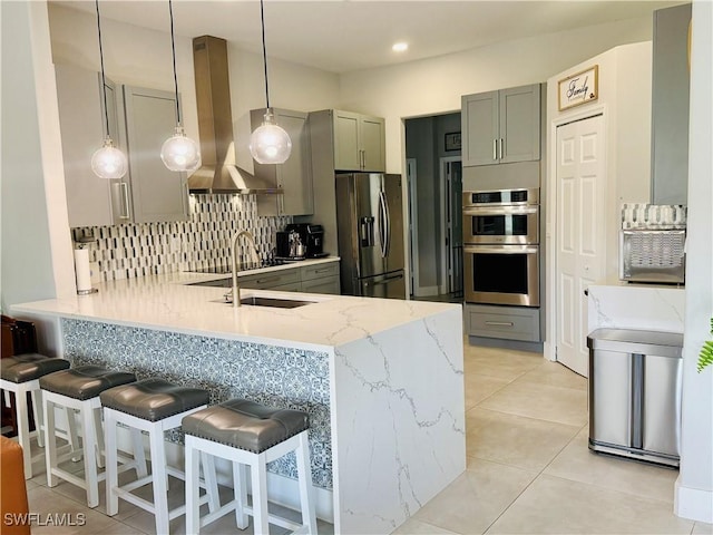 kitchen with stainless steel appliances, gray cabinets, backsplash, wall chimney range hood, and a peninsula