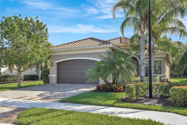 mediterranean / spanish-style home featuring stucco siding, a tile roof, decorative driveway, and a garage