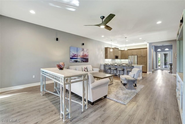 living room featuring a ceiling fan, recessed lighting, baseboards, and light wood-type flooring