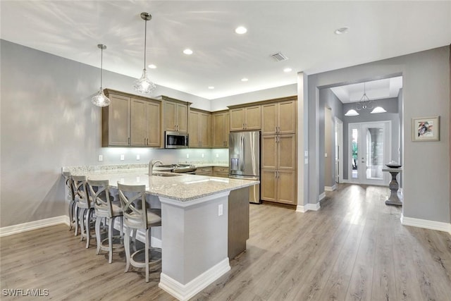 kitchen with visible vents, appliances with stainless steel finishes, a peninsula, light wood finished floors, and baseboards