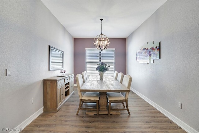 dining room featuring a notable chandelier, light wood-type flooring, and baseboards