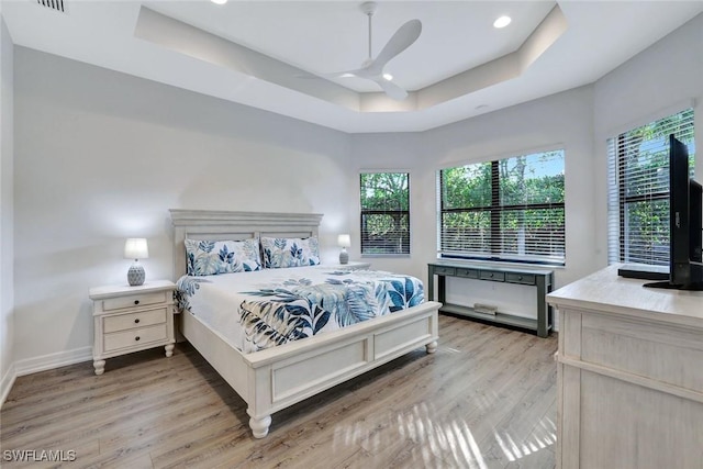 bedroom featuring baseboards, recessed lighting, light wood-style flooring, a raised ceiling, and a ceiling fan