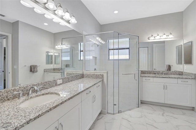 full bathroom with a shower stall, two vanities, marble finish floor, and a sink