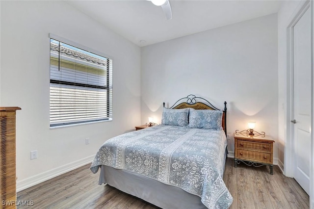 bedroom featuring baseboards, wood finished floors, and a ceiling fan