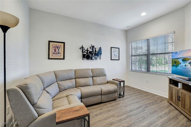 living room with recessed lighting, baseboards, and light wood-style floors