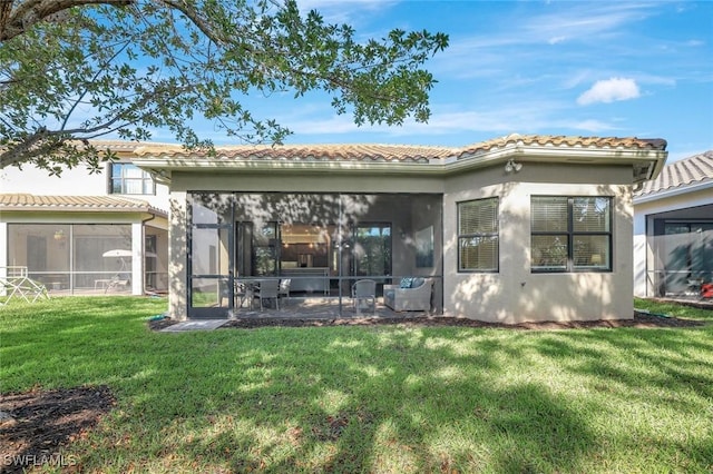 back of property with a tile roof, a lawn, a sunroom, and stucco siding