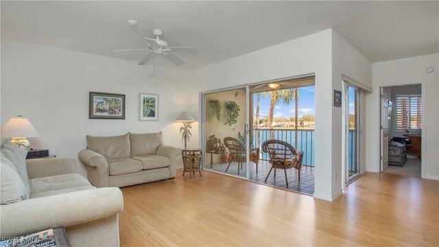 living area featuring baseboards, a ceiling fan, and wood finished floors