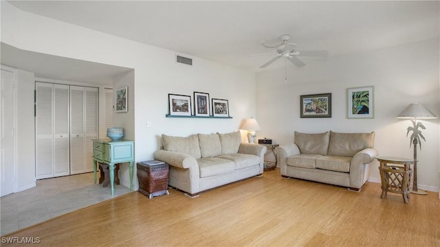 living room with ceiling fan, light wood-type flooring, visible vents, and baseboards