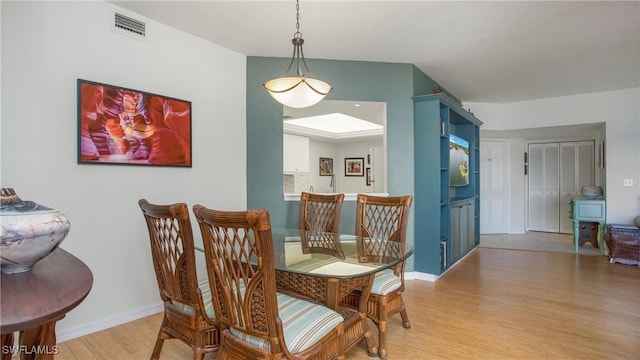 dining space featuring light wood finished floors, baseboards, and visible vents