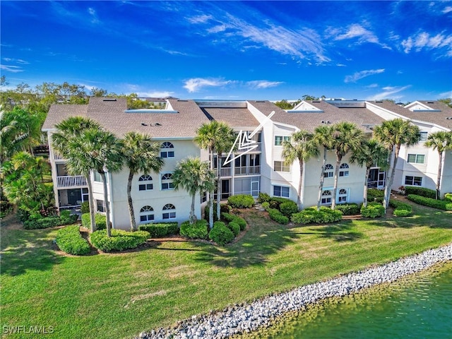 back of property with a garage, a water view, a yard, and stucco siding