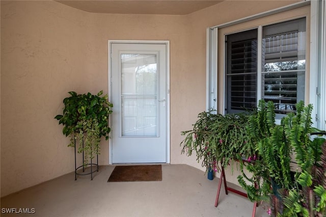 doorway to property featuring stucco siding