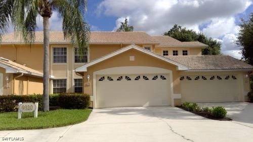 traditional home featuring driveway, an attached garage, and stucco siding