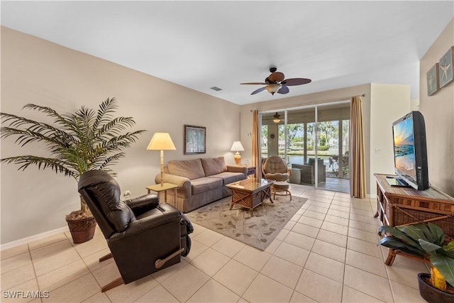 living room featuring light tile patterned flooring, visible vents, ceiling fan, and baseboards