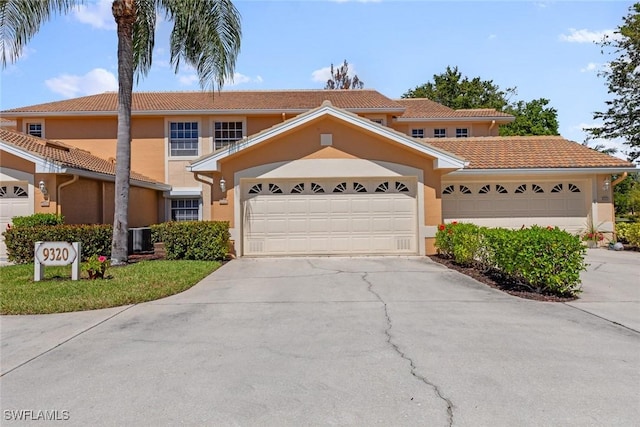 view of front of property with stucco siding, a tiled roof, concrete driveway, and a garage