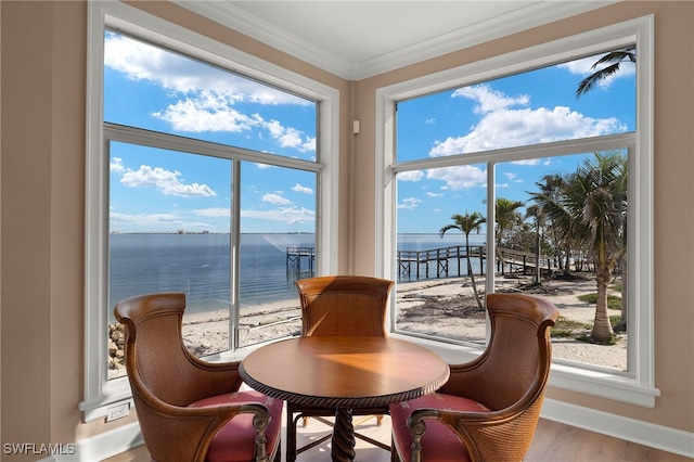 interior space with a water view, crown molding, baseboards, and wood finished floors