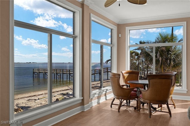 sunroom / solarium with ceiling fan and a water view