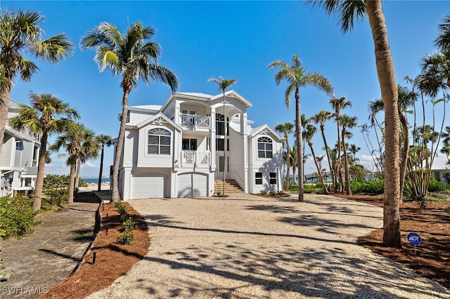 beach home featuring driveway, an attached garage, a balcony, and stucco siding