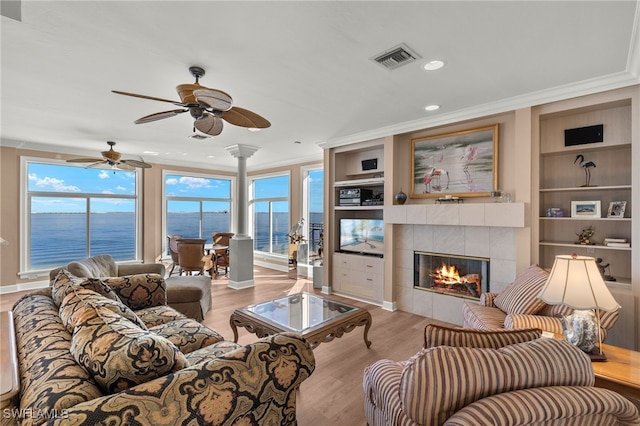 living area with ornamental molding, a wealth of natural light, light wood-type flooring, and visible vents