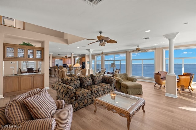 living area featuring visible vents, decorative columns, and light wood-style floors