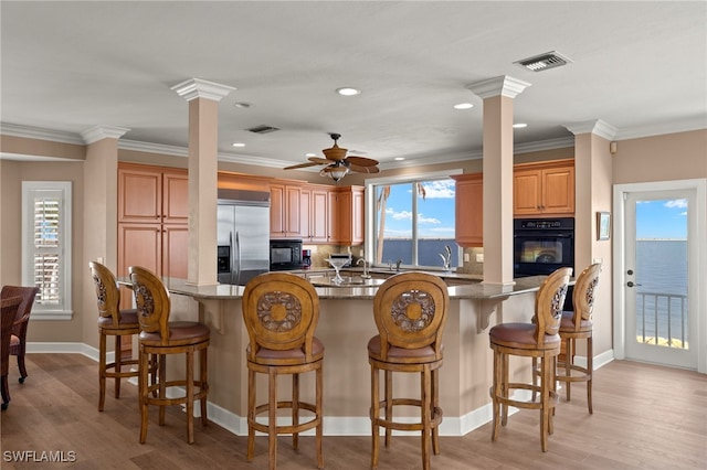 kitchen featuring visible vents, black appliances, decorative columns, and crown molding