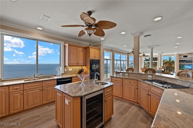 kitchen with beverage cooler, black appliances, a sink, and crown molding