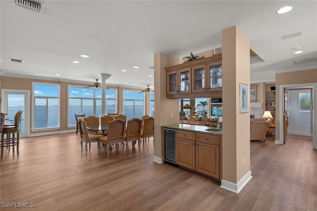 interior space featuring a wealth of natural light, beverage cooler, visible vents, and light wood-style flooring